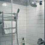 Douche moderne avec eau courante sur paroi en verre, illustration consommation d'eau par douche
