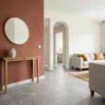 Entrée ouverte sur le salon délimitée par une cloison couleur terracotta contrastant avec des murs blancs cassés
