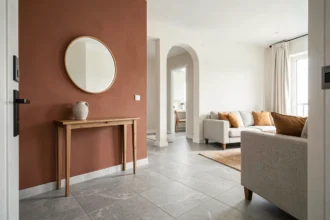 Entrée ouverte sur le salon délimitée par une cloison couleur terracotta contrastant avec des murs blancs cassés