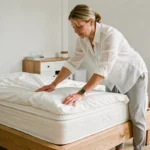 Femme qui pose une protection de matelas sur un lit en bois dans une chambre de style scandinave