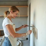 Femme appliquant de l'enduit sur un mur lors de la rénovation d'un studio en mode DIY